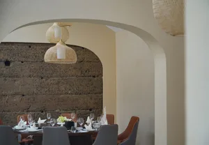 Elegant dining space with a long table set for dinner, surrounded by chairs and wine glasses, under warm and sophisticated lighting