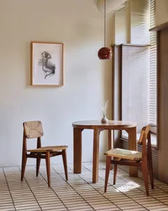 Dining table in a well-lit living area with two chairs and a vase, near a window