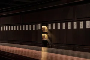 A wooden bar counter with bottles and books arranged in a decorative display, creating an inviting atmosphere for patrons