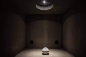 Empty room with a white vase on a concrete floor, dimly lit for a mysterious atmosphere