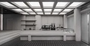 A spacious kitchen dining area with white walls, high ceilings, and a countertop with various items, surrounded by chairs