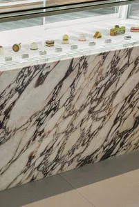 A kitchen with a marble countertop featuring various items displayed, including bottles, cups, and cakes