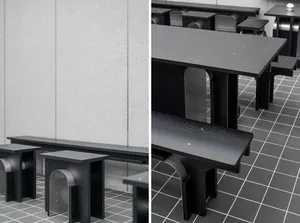 Industrial dining space with a metal table and wooden chairs, surrounded by a concrete wall and natural light