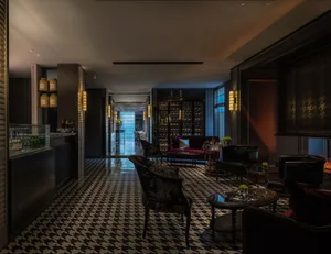 A modern and sophisticated hotel lobby with a black and white checkered floor, featuring various pieces of furniture and decorative bottles