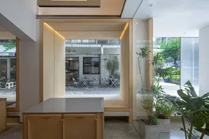 Warm kitchen with wooden cabinets, a dining table, and chairs, lit by natural sunlight through windows