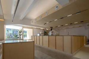 Clean and organized kitchen with wooden cabinets, countertops, and coffee makers, with cups placed around the space