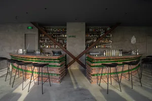 Cozy bar area with brick walls, a countertop, and bottles displayed on the wall, creating a rustic atmosphere