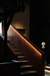 A well-lit interior staircase with wooden steps and railings, suggesting a warm and inviting environment