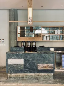 Modern kitchen showroom with a marble countertop, granite counter, and coffee machines on display, surrounded by scattered cups and a sophisticated atmosphere
