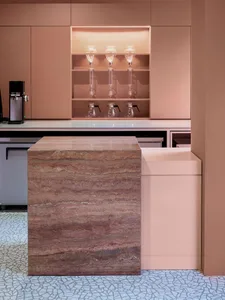 A modern kitchen with a marble countertop island, wine glasses, and a coffee maker, featuring warm and inviting lighting