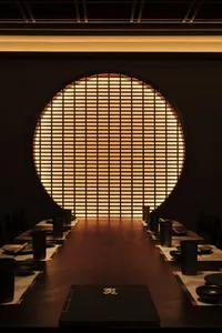 A cozy dining area with a round table surrounded by chairs, set with bowls and cups, in a restaurant-like setting