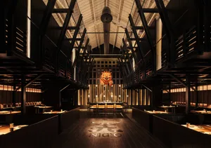 Warm and inviting restaurant interior with high ceilings, wooden floors, and multiple dining tables