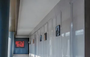 An empty hallway with white walls, grey floors, and artwork, lit by natural and artificial light, creating a calm and inviting atmosphere