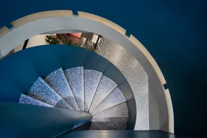 A modern staircase with metal steps and a minimalist design, set against a neutral background