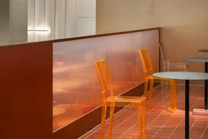 A modern dining area with a glass table and clear plastic chairs, surrounded by an inviting atmosphere