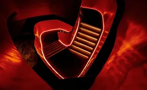 A warm and inviting staircase in a red building, featuring wooden steps and a metal railing, with a handrail for safety
