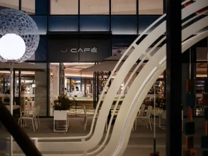 A modern cafe with several tables and chairs, white walls, and an inviting atmosphere