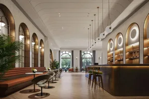 A well-lit hotel lobby with high ceilings, chairs, dining tables, and potted plants, creating a welcoming atmosphere