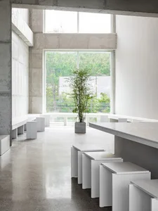 A large white building interior with multiple wooden benches in a clean and minimalistic space