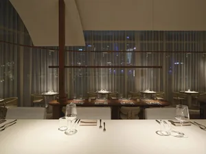 Sophisticated restaurant interior with a large dining table, wooden chairs, and fine china and glassware