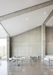 Empty modern lobby with concrete walls and floors, featuring chairs and a calm atmosphere