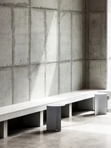 A public space with a textured concrete wall and two benches, creating a functional and minimalist atmosphere