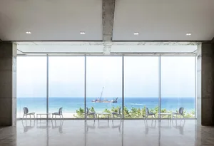 Open coastal living space with large windows, chairs, and a serene atmosphere