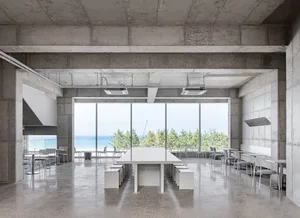 A spacious dining area with a large white table surrounded by chairs, well-lit by natural sunlight through windows
