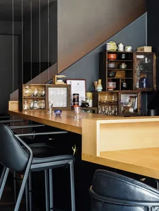 A cozy kitchen with wooden floors, cabinets, and countertops, featuring a dining table and chairs, with various objects and vases scattered throughout the space