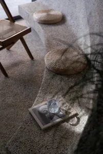 Cozy living area with a rugged floor, two chairs, a book, a cup, and a potted plant