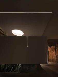 Modern living space with a large rock wall, clean lines, and natural and artificial lighting, featuring a dining table and windows