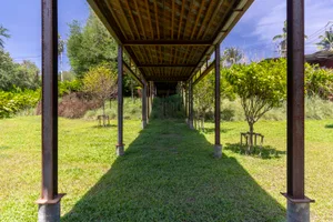 A wooden pavilion with a distinctive design features several benches for seating in a relaxing outdoor environment