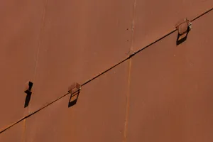 A close-up of a rusted metal wall with two small holes, possibly from a real or rendered architectural scene