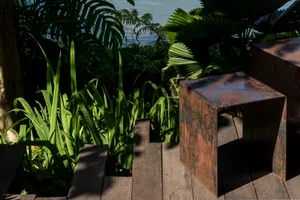 A wooden bench in a rustic outdoor patio area surrounded by plants and a staircase