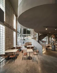 A modern restaurant interior with a spiral staircase, chairs, and dining tables, creating an inviting and comfortable atmosphere