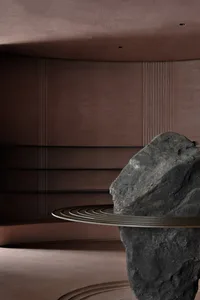 A modern living area with a brown color scheme and a large rock placed on a circular surface in the center of the room