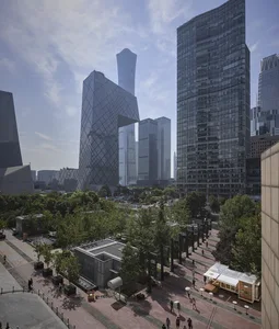一座現代玻璃帷幕城市大樓，周圍是熱鬧大都會區中行人穿梭的景象