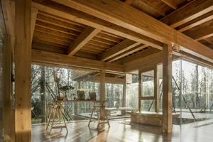 Warm and inviting open concept living area with wooden floors and walls, featuring a couch, dining table, chairs, and a bowl on the table