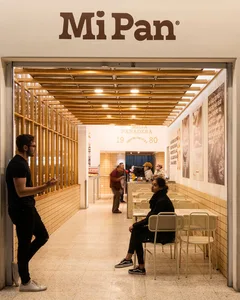 A bustling restaurant dining area with modern design elements, including an open ceiling, and comfortable seating for multiple people