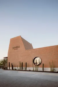 A modern house with a brick wall and cacti, featuring a round window and a warm, inviting atmosphere