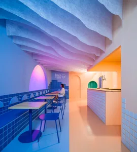 A modern restaurant interior with pink walls, dining tables, and chairs, creating a warm and inviting atmosphere