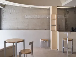 Modern kitchen with wood flooring, white walls, and a countertop, featuring two dining tables, chairs, and benches