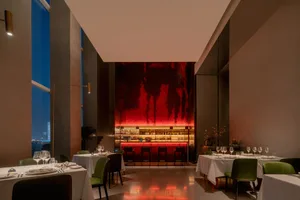 優雅餐廳內部，紅色強調牆、黑色檯面，以及擺放酒杯的餐桌