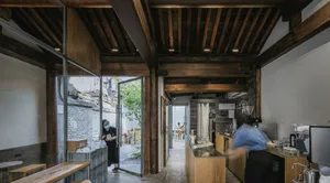 A warm and inviting restaurant interior with wooden floors and walls, featuring dining tables and chairs, and natural lighting