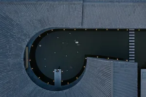 A relaxed indoor pool scene with a circular pool surrounded by a stone wall, people enjoying the poolside atmosphere
