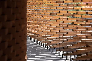 A calm and organized space with wooden benches arranged in rows on a concrete surface