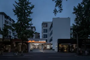 夜晚繁忙的城市街道，設有咖啡店與盆栽，門外停放自行車