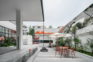 A modern coffee shop with a large window, chairs, dining tables, and potted plants, creating a bright and contemporary atmosphere