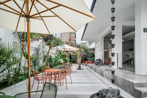 An inviting outdoor patio area with tables, chairs, umbrellas, and potted plants