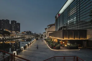 A waterfront restaurant with seating areas, potted plants, and a relaxing atmosphere at night